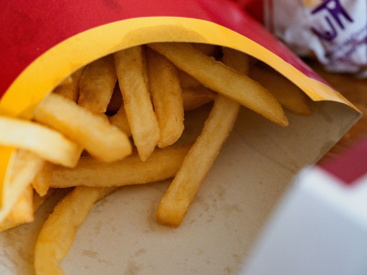 Close-up of crispy golden french fries in a takeaway box showcasing delicious fast food.