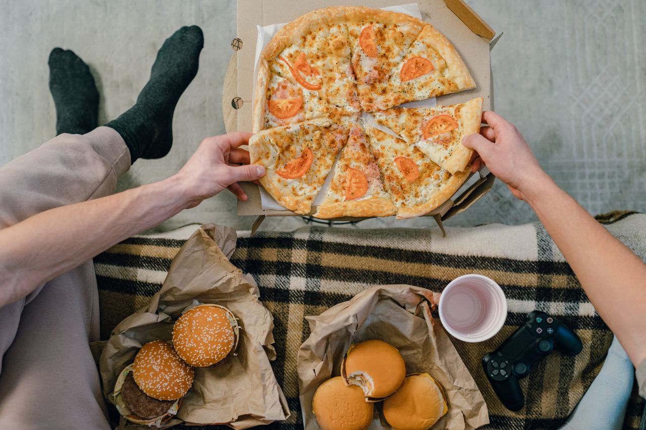 Cozy setup with pizza, burgers, and gaming controller, perfect for casual indoor hangouts.